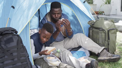 African-American-father-and-son-enjoy-a-meal-while-camping