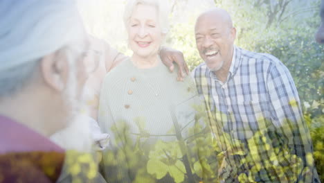 Animation-of-trees-over-diverse-senior-people-smiling-in-garden