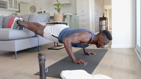 Focused-african-american-man-doing-push-ups-on-couch-in-sunny-living-room,-slow-motion