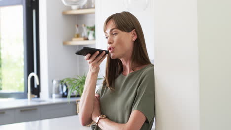 Middle-aged-Caucasian-woman-using-voice-command-on-smartphone-at-home