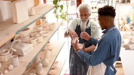 Happy-diverse-male-potters-discussing-about-work-in-pottery-studio,-slow-motion