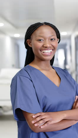 Vídeo-Vertical-Del-Retrato-De-Una-Feliz-Doctora-Afroamericana-En-El-Hospital,-Cámara-Lenta