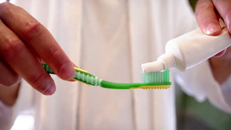 Midsection-of-biracial-man-putting-toothpaste-on-toothbrush,-slow-motion