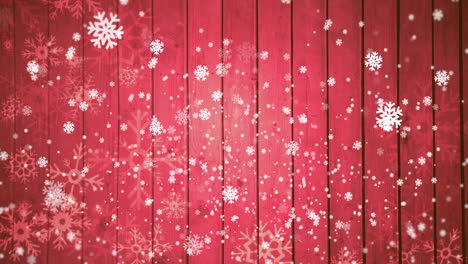 Animation-of-snow-falling-on-red-wooden-background-with-copy-space-at-christmas