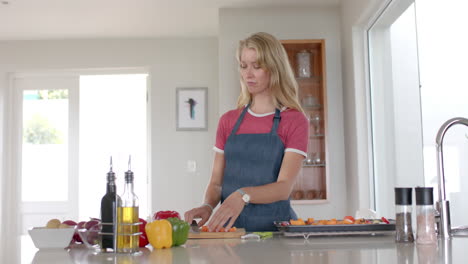 Portrait-of-happy-caucasian-woman-wearing-apron-and-cooking-in-kitchen,-slow-motion