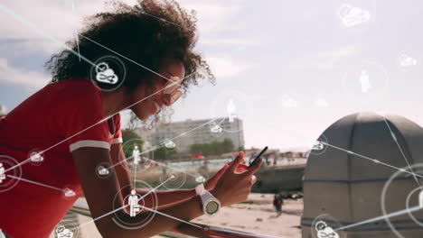 Animation-of-network-of-connections-with-icons-over-biracial-woman-using-smartphone-by-sea