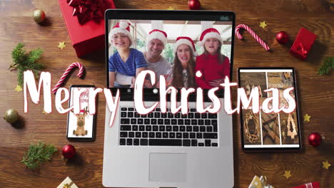 Animation-of-merry-christmas-text-over-decorations-and-caucasian-family-on-laptop-screen
