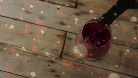 Composite-of-red-wine-being-poured-into-glass-over-wooden-background