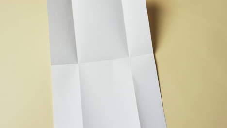 Video-Eines-Weißen-Blattes-Papier-Mit-Falten-Auf-Gelbem-Hintergrund