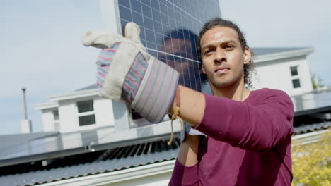 Busy-biracial-man-with-gloves-carrying-solar-panel-in-garden,-slow-motion