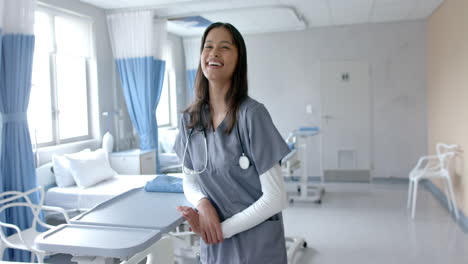 Portrait-of-happy-biracial-female-doctor-laughing-in-hospital-ward,-copy-space,-slow-motion