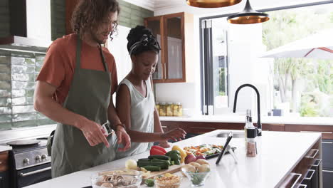 Diverse-couple,-a-young-African-American-woman-and-Caucasian-man,-cooking-together-at-home