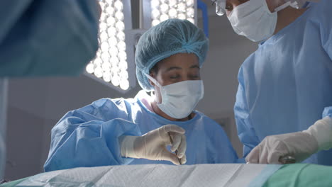Diverse-female-surgeons-operating-on-patient-in-operating-theatre,-slow-motion