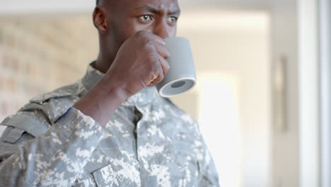 Pensive-african-american-male-soldier-drinking-coffee-and-looking-ahead-in-sunny-room,-slow-motion