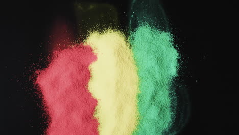 Video-of-red,-yellow-and-green-powders-with-copy-space-on-black-background