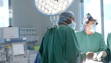 Diverse-female-and-male-surgeons-in-masks-checking-equipment-during-operation,-slow-motion
