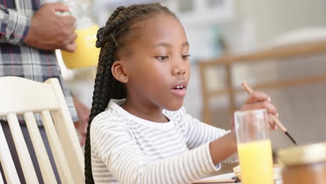 Happy-african-american-father-and-daughter-having-breakfast-at-home,-slow-motion