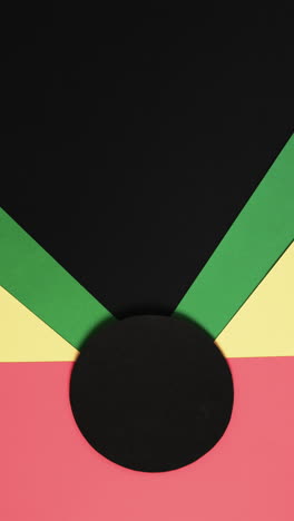 Vertical-video-of-red,-yellow-and-green-papers-with-copy-space-on-black-background