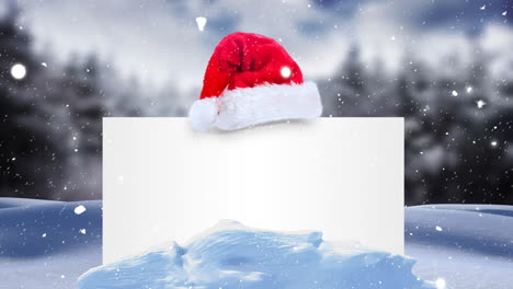 Animation-of-snow-falling-over-white-card-with-copy-space-and-santa-claus-hat-in-winter-scenery