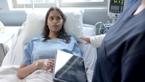 Paciente-Femenina-Diversa-En-Cama-De-Hospital-Y-Doctora-Usando-Tableta-Hablando,-Cámara-Lenta