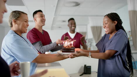 Diverse-male-and-female-doctors-celebrating-birthday-at-reception-desk-at-hospital,-slow-motion