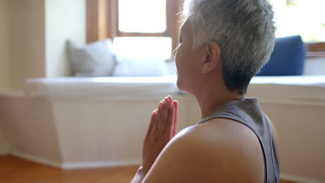 Fokussierte-ältere-Frau-Mit-Gemischter-Abstammung-Mit-Räucherstäbchen,-Die-Zu-Hause-Auf-Einer-Yogamatte-Meditiert
