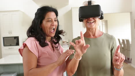 Happy-diverse-senior-women-using-vr-glasses-and-laughing-in-sunny-living-room,-slow-motion