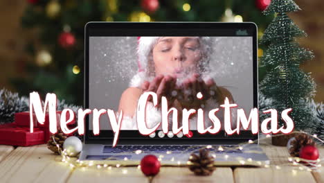 Animation-of-merry-christmas-text-over-snow-falling-and-caucasian-woman-on-laptop-screen