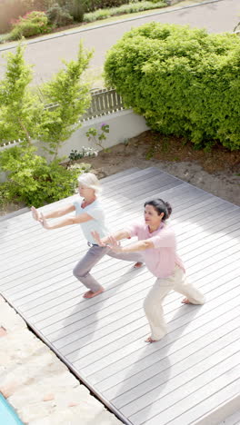 Zwei-Glückliche,-Vielfältige-Seniorinnen-Praktizieren-Yoga-Im-Sonnigen-Garten,-Zeitlupe