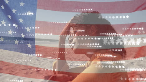 Animation-of-american-flag-and-stars-over-happy-african-american-woman-relaxing-on-sunny-beach