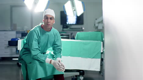 Caucasian-male-surgeon-wearing-surgical-gown-sitting-in-operating-theatre,-copy-space-slow-motion