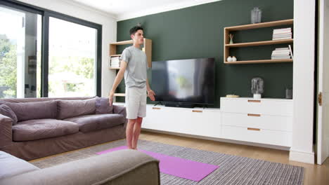 Fokussierter-Biracial-Mann,-Der-Yoga-Im-Wohnzimmer-Praktiziert,-Kopierraum,-Zeitlupe