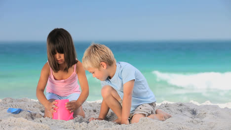 Cute-boy-building-a-sand-castle-with-his-sister