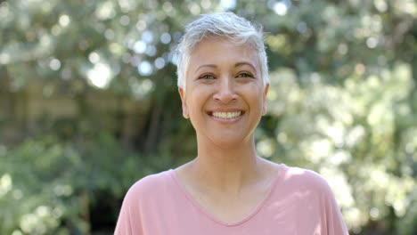 Portrait-of-happy-senior-biracial-woman-with-short-hair-in-sunny-garden-at-home,-slow-motion