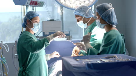 Diverse-female-and-male-surgeons-in-masks-passing-surgical-tools-during-operation,-slow-motion