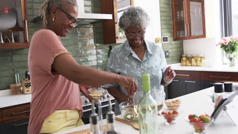 Happy-senior-african-american-female-friends-preparing-meal-in-kitchen,-copy-space,-slow-motion