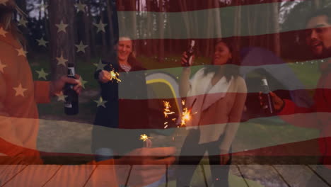 Animation-Der-Amerikanischen-Flagge-über-Verschiedenen-Freunden,-Die-Auf-Einem-Campingplatz-Bier-Trinken-Und-Spaß-Mit-Wunderkerzen-Haben
