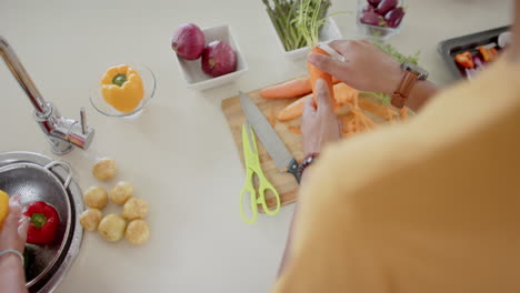 Diverse-couple-preparing-and-washing-fresh-vegetables-in-kitchen,-slow-motion