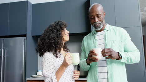 Happy-biracial-couple-talking-and-pouring-coffee-in-kitchen,-slow-motion