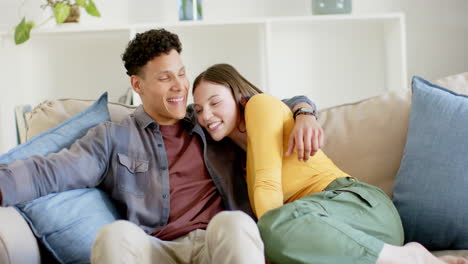 Portrait-of-happy-diverse-couple-sitting-on-sofa-embracing-at-home,-in-slow-motion