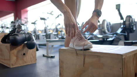 Person-tying-shoelaces-at-the-gym,-with-copy-space