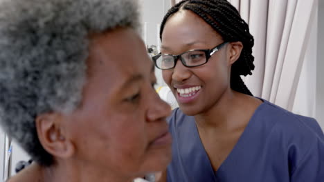 Doctora-Afroamericana-Probando-El-Oído-De-Una-Paciente-Mayor-En-La-Habitación-Del-Hospital,-Cámara-Lenta