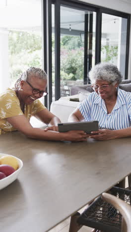 Vertical-video-of-happy-senior-african-american-female-friends-using-tablet,-copy-space,-slow-motion