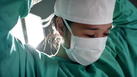 Asian-female-surgeon-wearing-face-mask-in-operating-theatre-at-hospital,-slow-motion