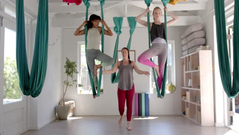 Focused-diverse-fitness-teenage-girls-in-aerial-yoga-class-in-big-white-room,-slow-motion