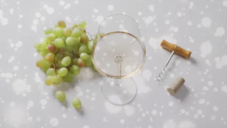 Composite-of-glass-of-white-wine,-grapes-and-corkscrew-over-vineyard-background