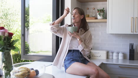 Middle-aged-Caucasian-woman-enjoys-a-meal-at-home,-with-copy-space