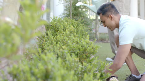 Happy-diverse-gay-male-couple-gardening-in-sunny-garden,-copy-space,-slow-motion,-copy-space
