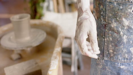 Dirty-hand-of-biracial-male-potter,-standing-in-pottery-studio,-slow-motion