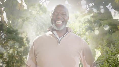 Animation-Von-Lichtflecken-Und-Bäumen-über-Einem-Lächelnden-älteren-Afroamerikanischen-Mann-Im-Garten